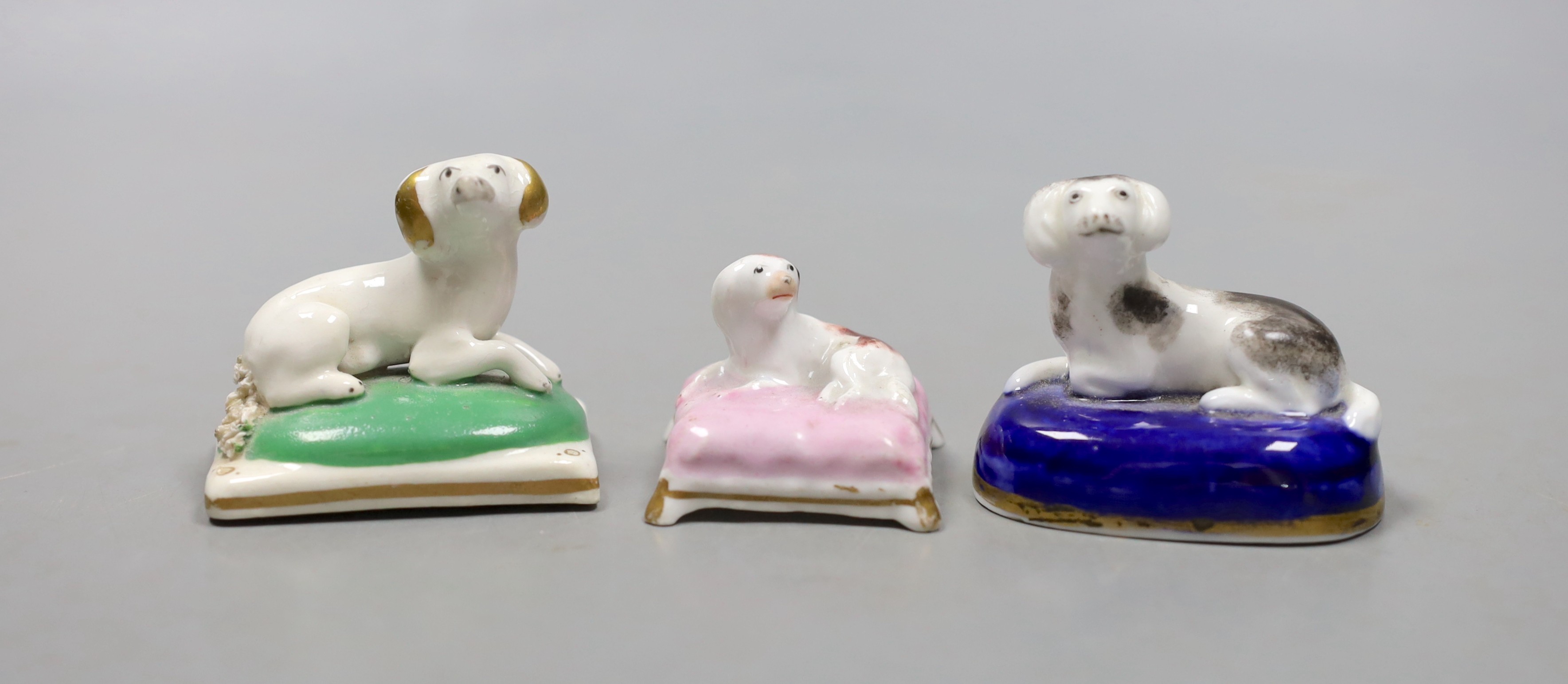 Two English porcelain models of recumbent king Charles spaniels, possibly Davenport, c.1830–50, 5.3cm long and a similar Staffordshire porcelain model on a pink cushion (3), Provenance- Dennis G Rice collection